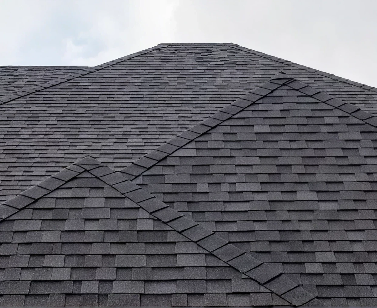Dark shingle roof against cloudy sky